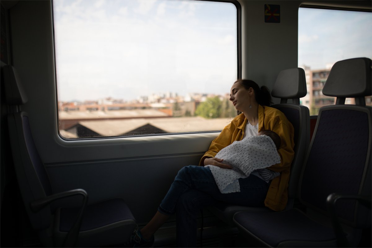 young mother breastfeeding baby on train