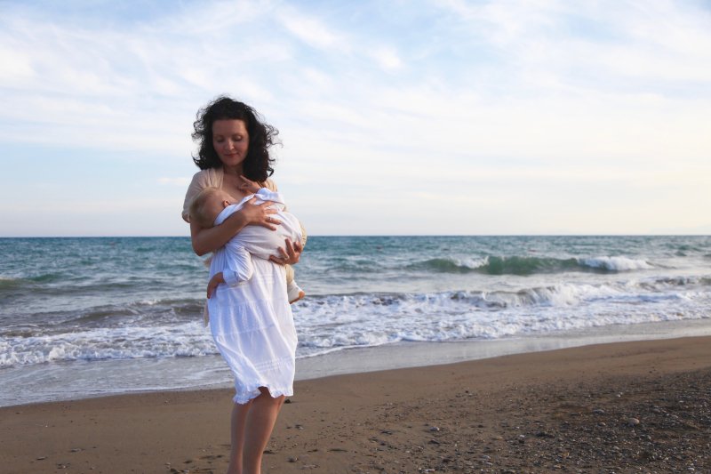 woman breastfeeding baby on a beach