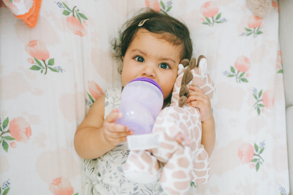 a cute baby girl drinking milk from a bottle